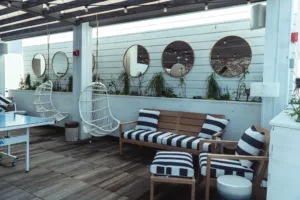 Elite L.A. Patios - Why Metal Patio Covers Are Perfect for Southern California Weather - interior with white walls round mirrors and striped cushions on wooden furniture